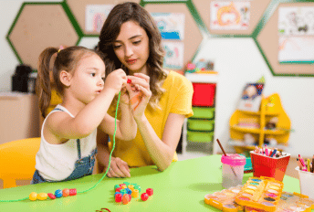 Woman working with elementary aged girl with find motor skills